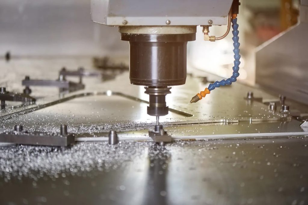 CNC machine cutting a metal workpiece with visible chips and coolant spray during operation.