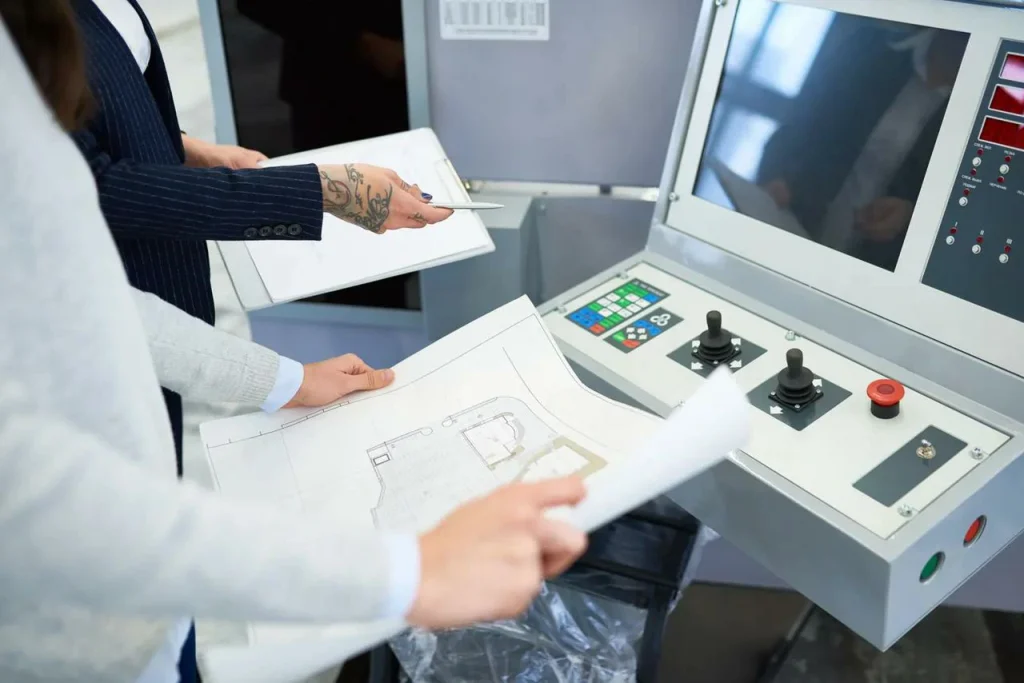 Inženýři kontrolují výkresy na řídicím panelu CNC, plánují předvýrobu, aplikují zásady GD&T na návrh obráběcího procesu.