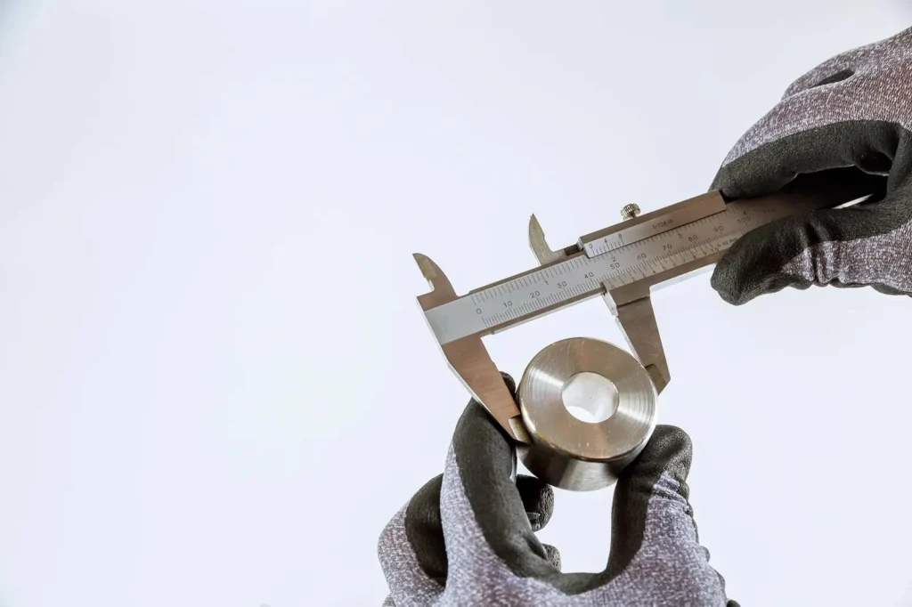 Un calibre vernier mide una pieza cilíndrica metálica durante el control de calidad, verificando la precisión de las dimensiones y las roscas procedentes del roscado y el fresado de roscas.
