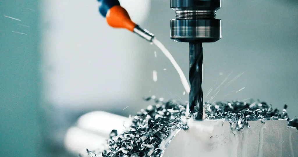 CNC milling machine cutting metal with coolant, producing precision components with complex geometries in modern manufacturing.