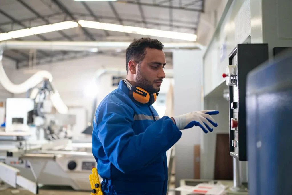 An engineer programs a CNC machine’s control panel, a labour factor in calculating machining costs.