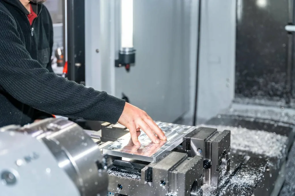 Technik nastavující CNC stroj, aby zajistil přesné nastavení a omezil výrobní odpad.