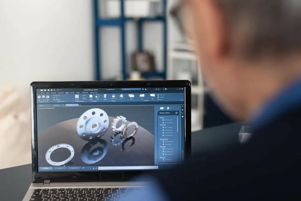 CNCフライス加工や旋盤加工の準備のため、ノートパソコンで3D歯車モデルを検討する設計者。