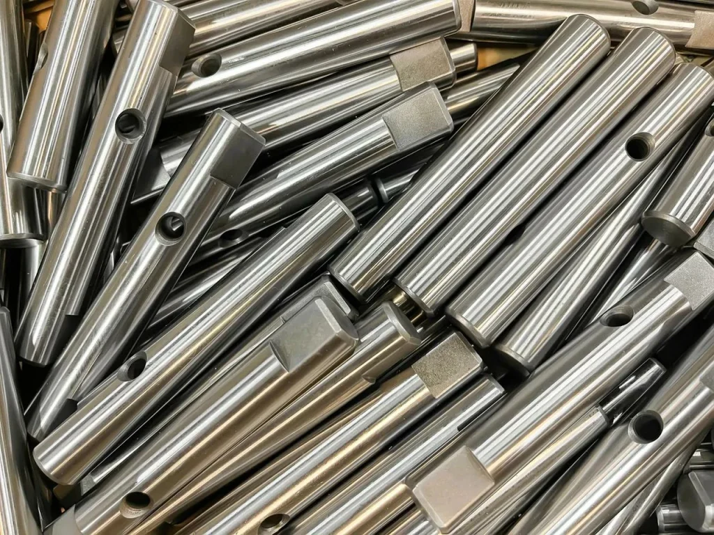 Una pila di aste metalliche mostra la texture liscia e lineare di una finitura in metallo spazzolato.