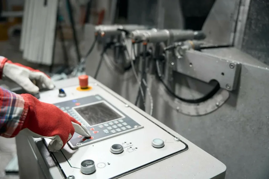Un ouvrier utilise un panneau de commande CNC pour programmer une séquence de taraudage de trous borgnes.