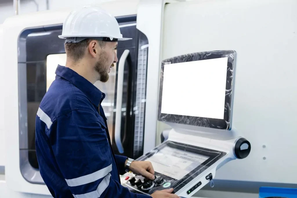 A factory operator programs a machine to produce standard nut and bolt parts.