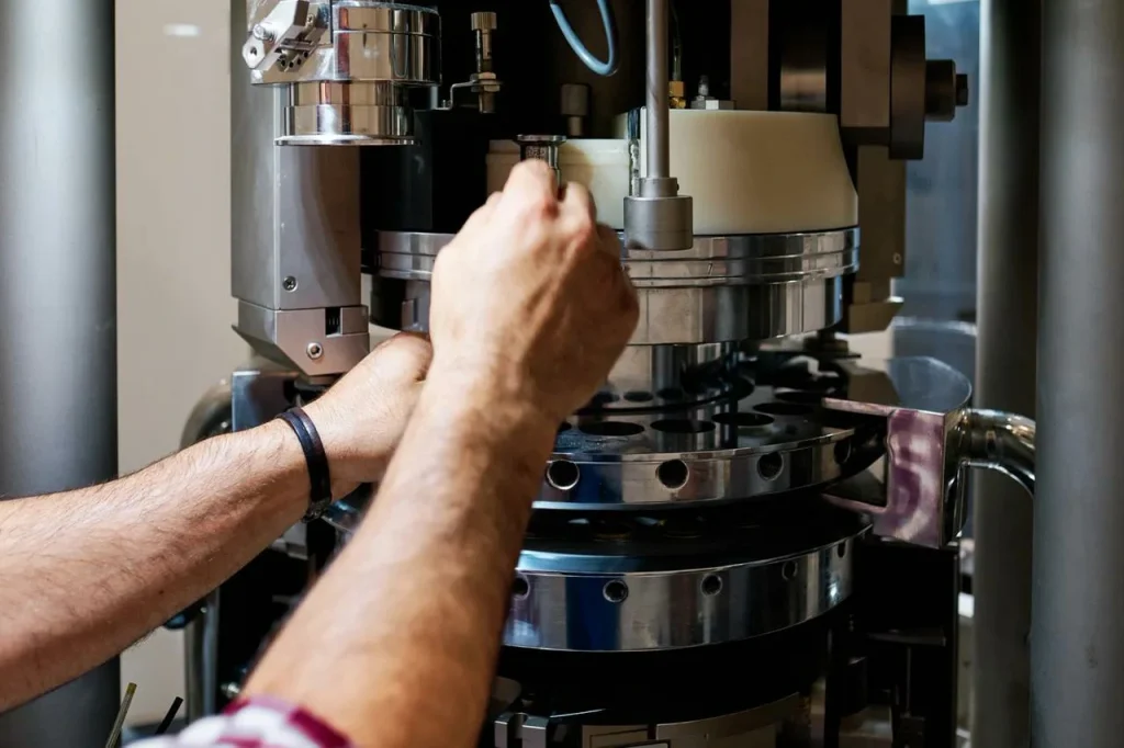 Technik seřizuje průmyslové stroje a porovnává CNC obrábění s procesy 3D tisku.