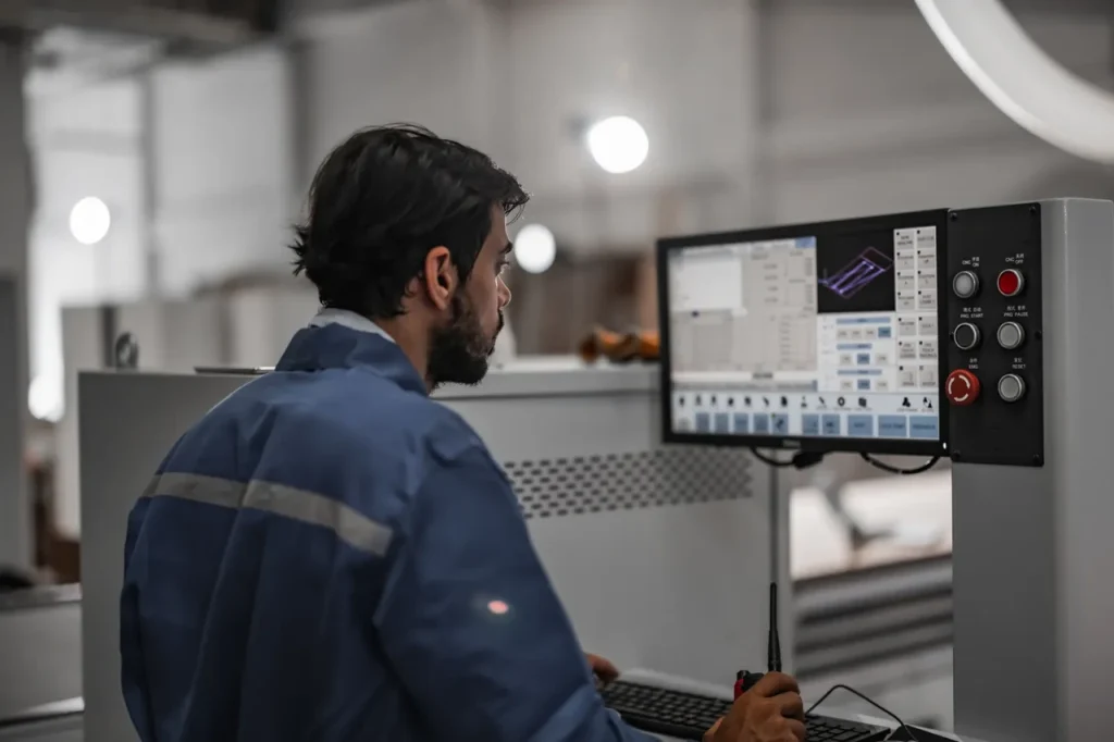 CNC-Bediener bei der Programmierung eines Bearbeitungsauftrags für Messing-/Bronzeteile, wobei die Bearbeitungsparameter und die Effizienz der beiden Legierungen verglichen werden.