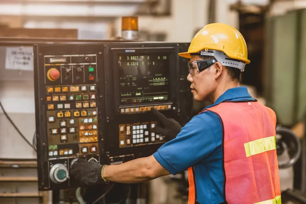Ingegnere esperto che opera su un pannello di controllo di una macchina CNC, assicurando l'accuratezza nei processi di microlavorazione CNC ad alta precisione