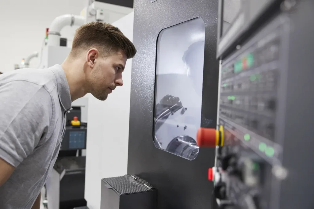 Ingeniero inspeccionando una máquina CNC, evaluando el rendimiento del proceso de mecanizado.