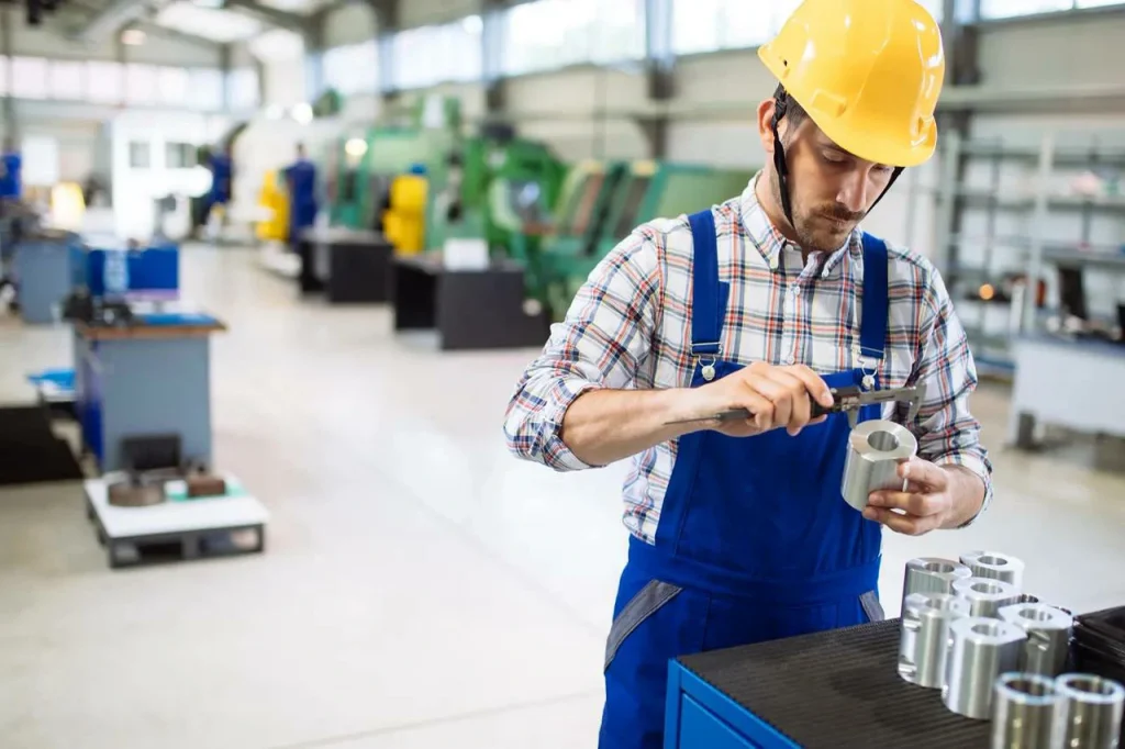 Ein Techniker prüft einen Metallzylinder, um sich von der gleichmäßigen Edelmetallbeschichtung zu überzeugen.