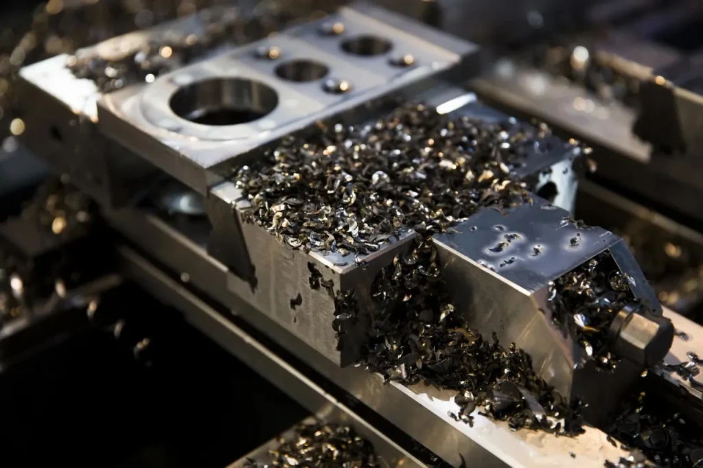 Primo piano di parti lavorate CNC di precisione in metallo coperte di trucioli metallici, che evidenziano i processi di microlavorazione CNC