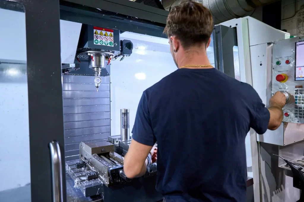 An operator runs a CNC mill to create countersink or counterbore features.