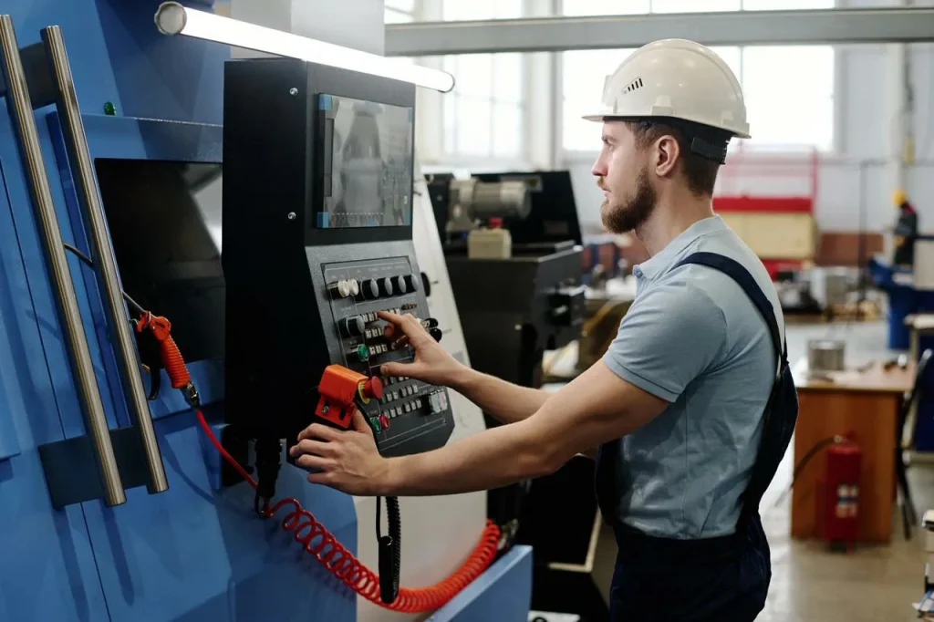Ein Fabrikarbeiter programmiert eine Maschine zur Bearbeitung von Aluminiumguss.