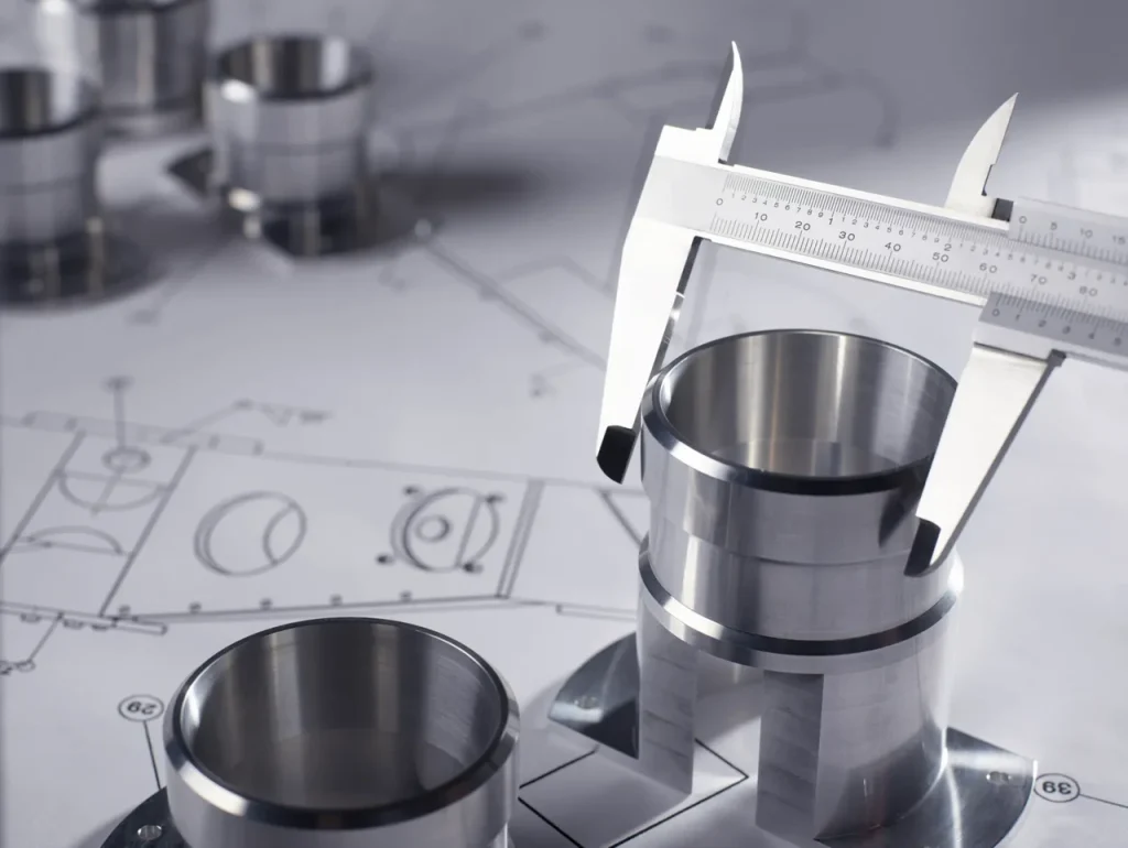 Técnico que mide una pieza metálica mecanizada con calibradores, verificando las dimensiones para evitar tolerancias que provoquen el gripado del metal.