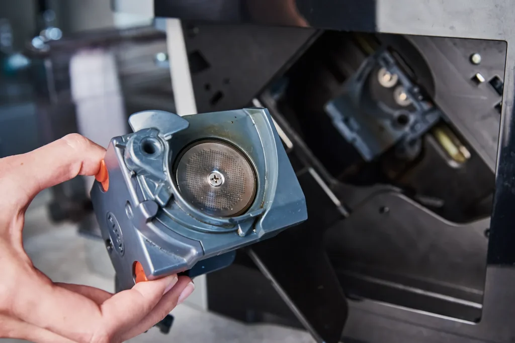 A hand holding a finished CNC-machined aerospace part near its industrial equipment.