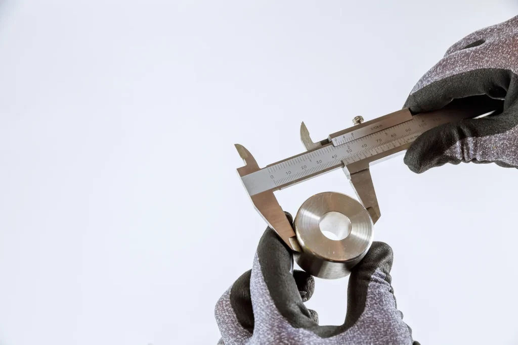 A worker measures a precision metal component after CNC turning.