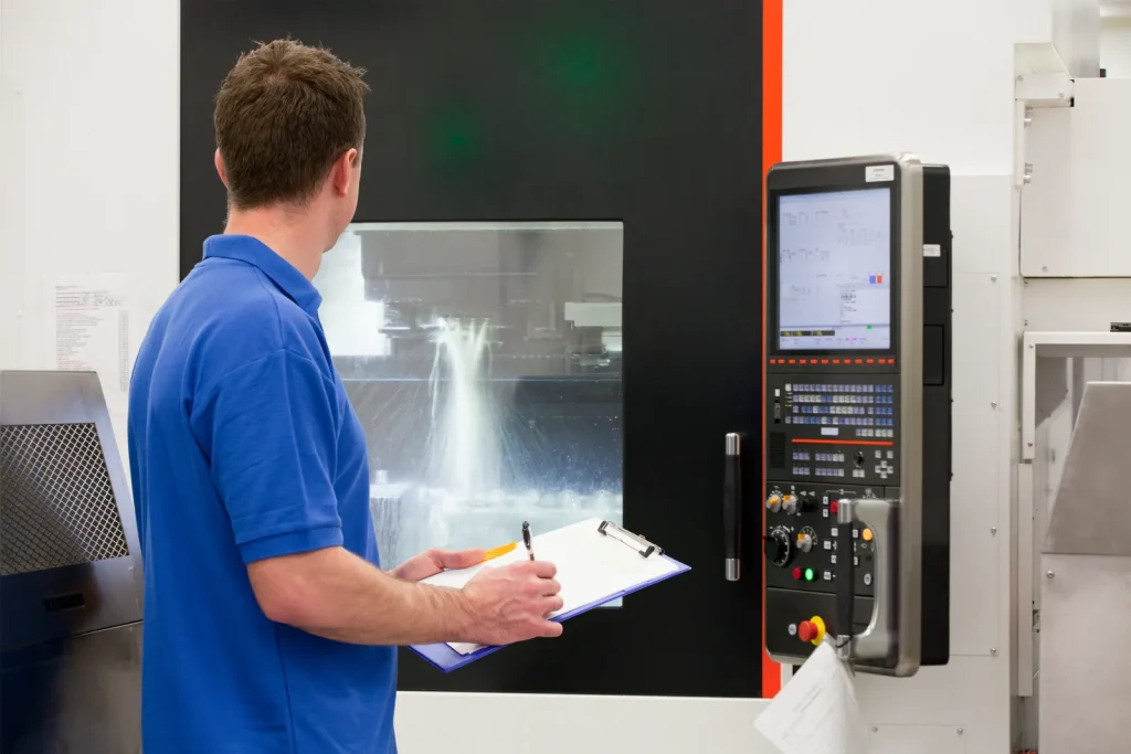 A technician monitors a CNC machine, contrasting it with the forming nature of forging.