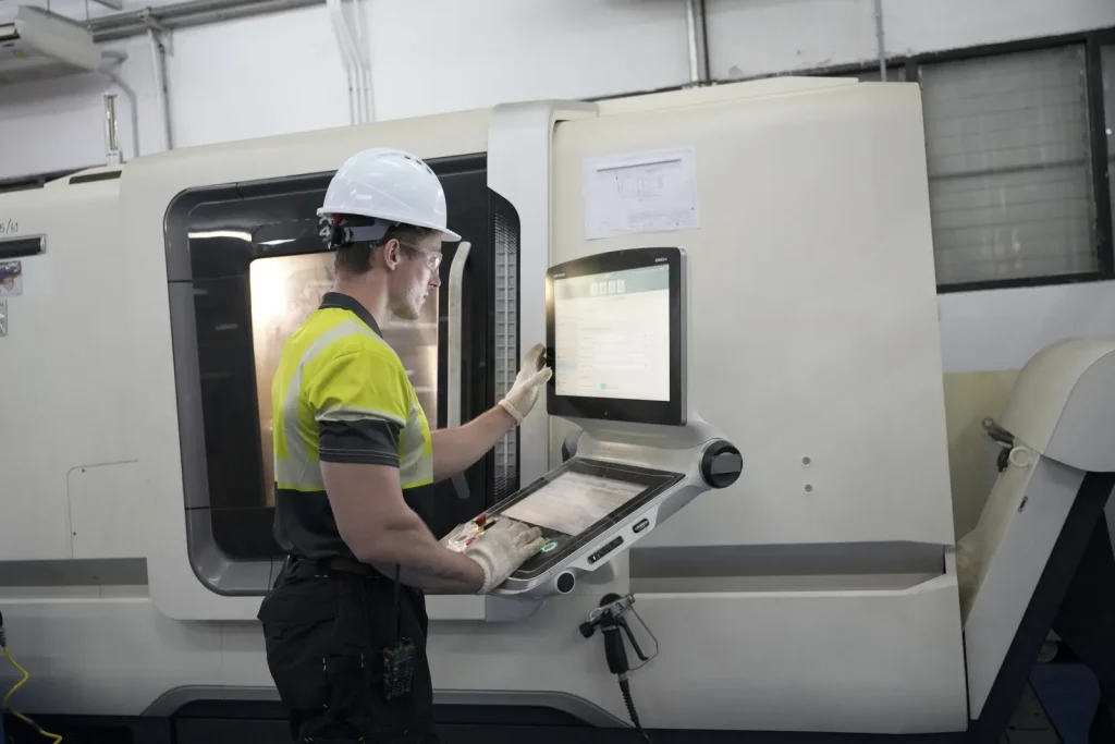 A technician operates a high-precision CNC milling machine in a factory setting.