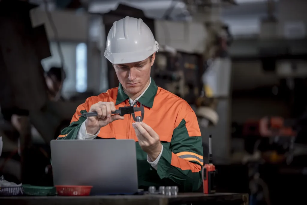Un ingénieur inspecte un composant produit par usinage de métaux réfractaires.