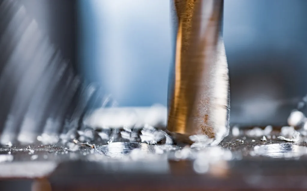 Primo piano di un utensile CNC che taglia il metallo, mostrando i trucioli e il movimento del mandrino durante la lavorazione industriale.