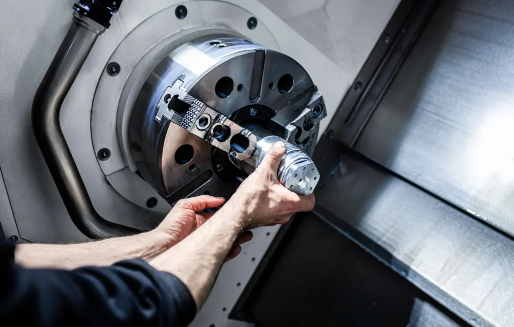 Praktische Montage eines Metallwerkstücks auf einem CNC-Drehfutter mit Schwerpunkt auf Präzisionsbearbeitung vor der Endmontage mit verschiedenen Schraubentypen.