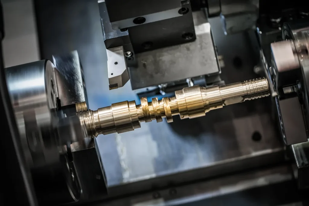  Dynamic close-up of CNC lathe processing brass stepped shaft workpiece, cutting tool poised above rotating metal part for precision turning.