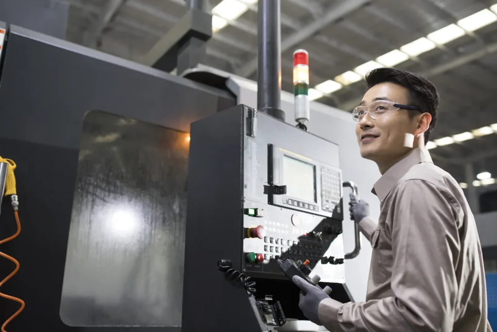 An engineer adjusts a CNC machine to ensure parts meet required machining tolerances.