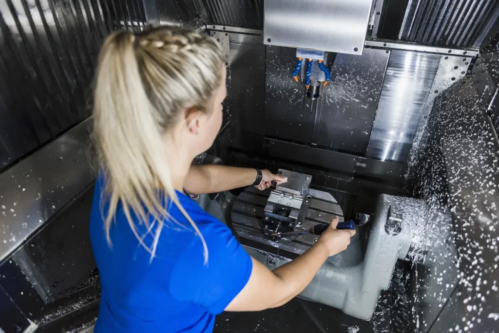 An operator works with a high-speed CNC milling machine during production.