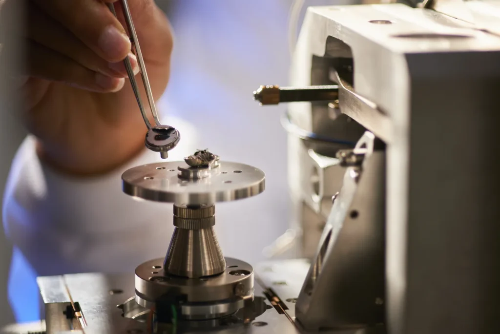 Technicien utilisant des pinces pour manipuler un petit composant lors d'un montage d'usinage de précision dans un laboratoire de fabrication médicale.