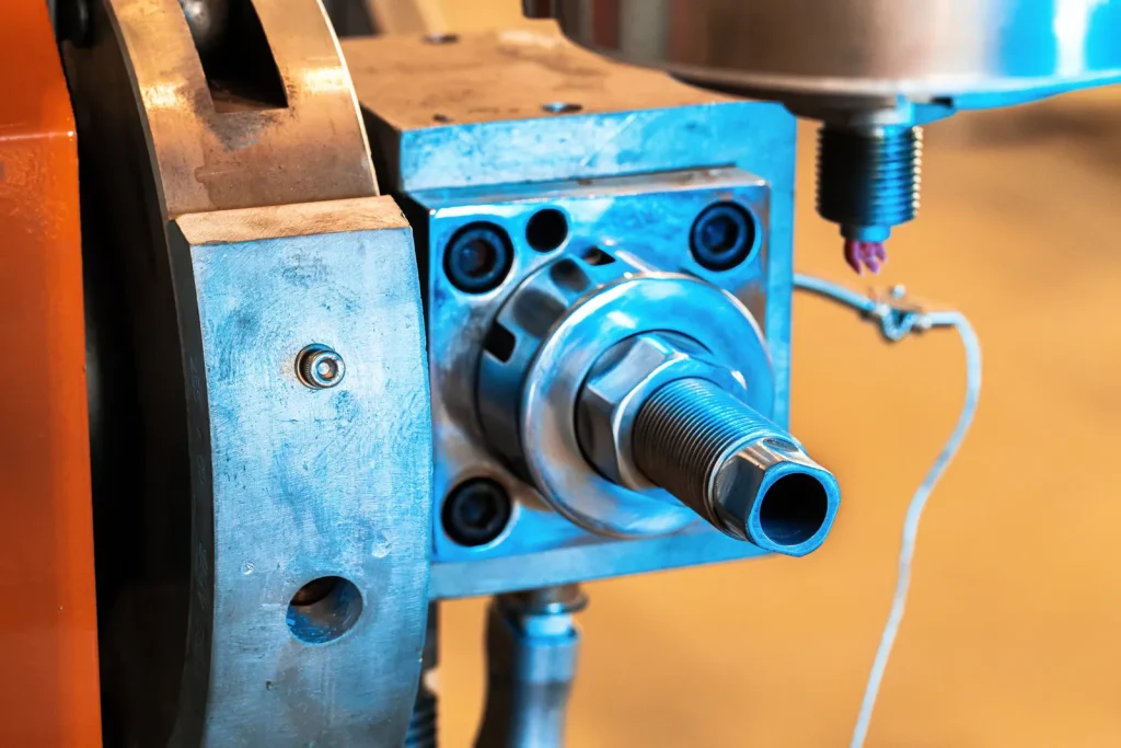 Gros plan sur la broche d'un dispositif de fixation métallique montée sur une machine-outil, mettant en évidence un arbre creux à filetage de précision usiné par un équipement à commande numérique destiné à l'outillage industriel.