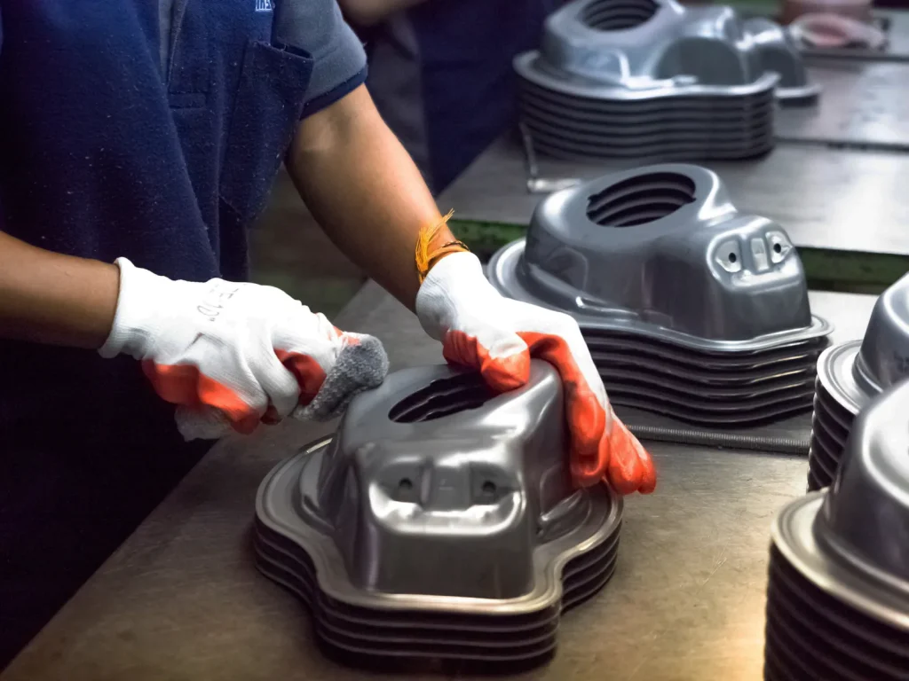 Worker cleaning a CNC-machined metal part to achieve a smooth, uniform surface finish.